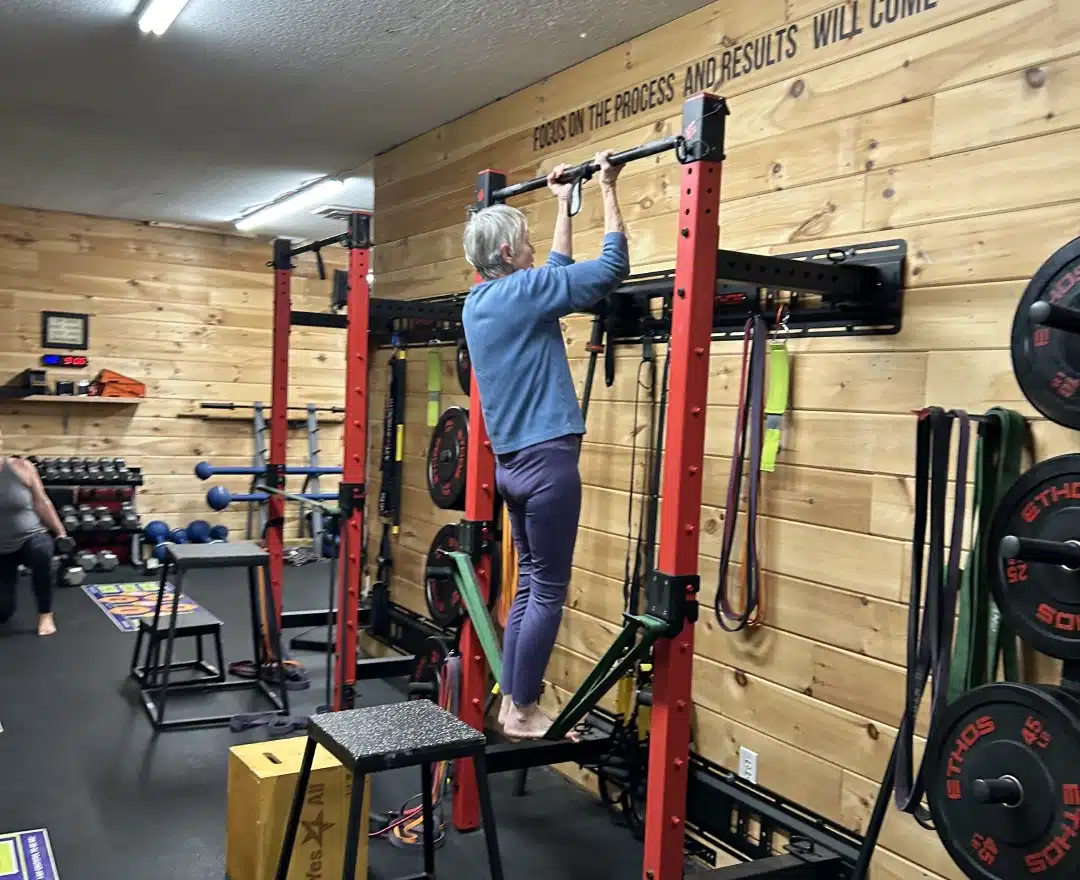 A member using the assisted pull-up rig, supported by resistance bands