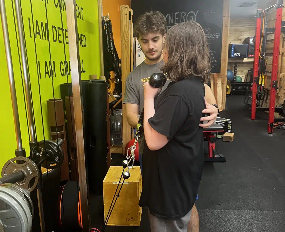 A coach guiding a member through a dumbbell exercise one-to-one