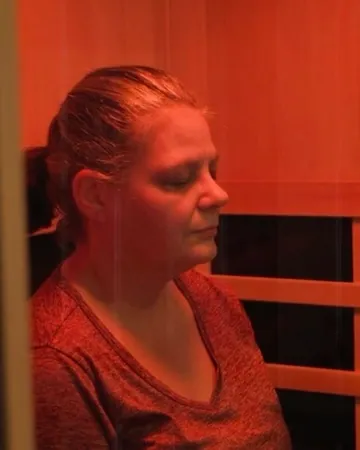 A member sitting under the red light therapy panel