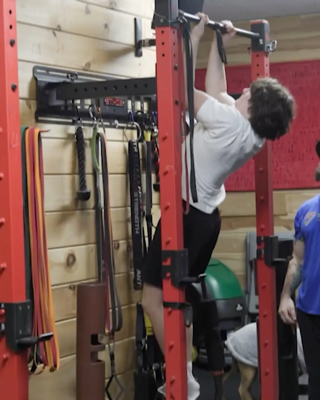 A member doing pull-ups on the red power rack